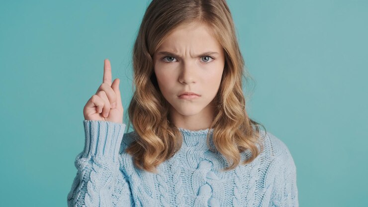 serious-blond-teenage-girl-looking-aggressive-keeping-index-finger-up-blue-background-silence-gesture-angry-girl_574295-2439