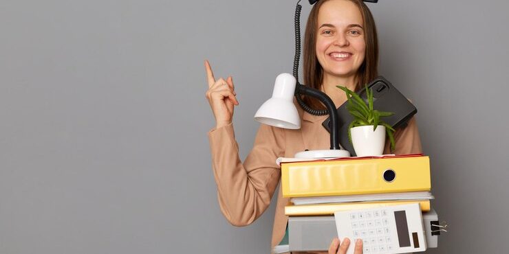 portrait-funny-young-pretty-woman-wearing-beige-jacket-holding-documents-her-office-stuff-posing-with-phone-her-head-isolated-gray-background-showing-advertisement-area_176532-23056