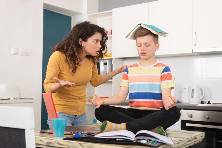child-is-sitting-table-holding-book-his-head-doing-yoga-surprised-mother-watches_623487-315